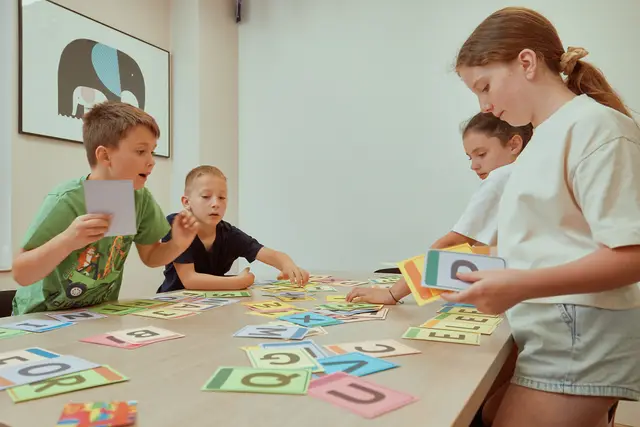 Children playing a letter card game at a table