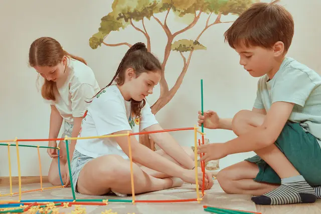 Children building shapes from colourful sticks on the floor