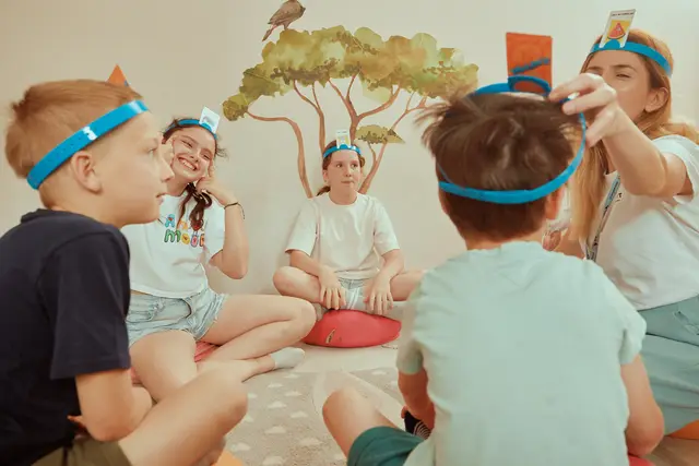 Children sitting in a circle playing a headband guessing game