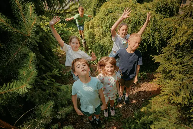 Children waving among the trees in the garden